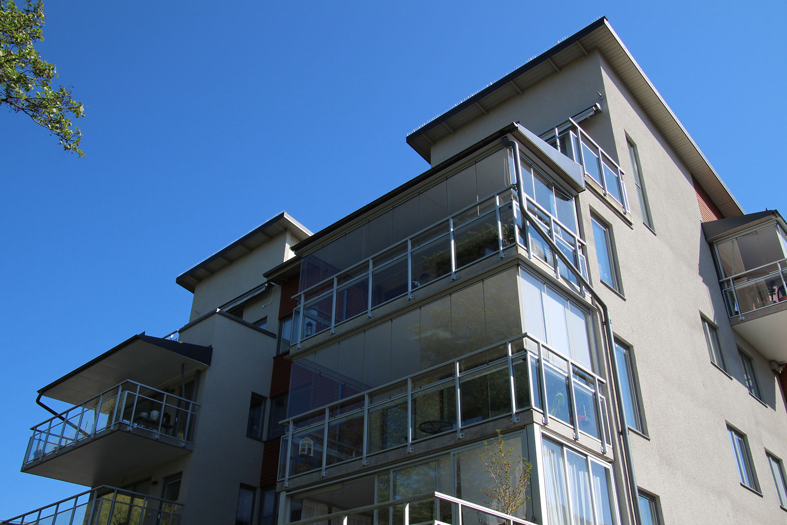 Färdigt bostadshus med inglasade balkonger mot klarblå himmel